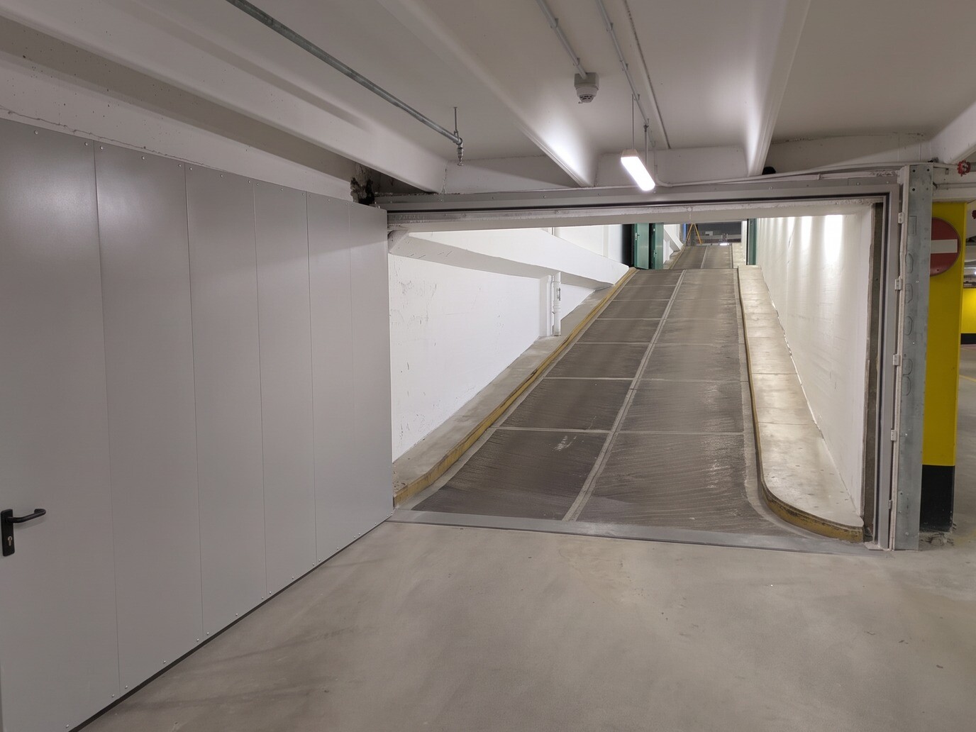 Portone tagliafuoco a battente ITAL SWING grigio aperto sulla rampa di un parcheggio interrato